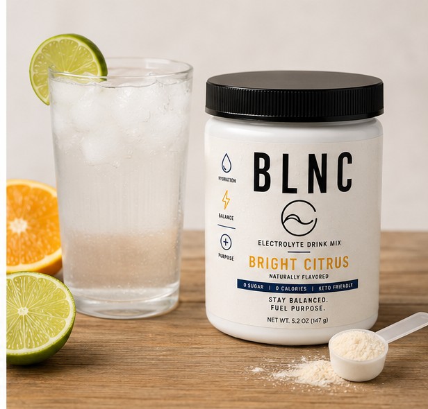 A tall glass of ice water beside the BLNC jar and a measured scoop.